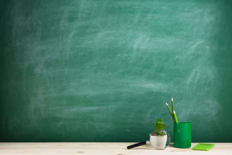 education-concept-school-supplies-desk-auditorium-blackboard-background-min